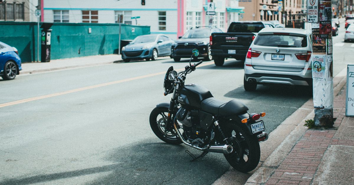 Motocicleta estacionada em uma rua urbana movimentada, entre outros veículos