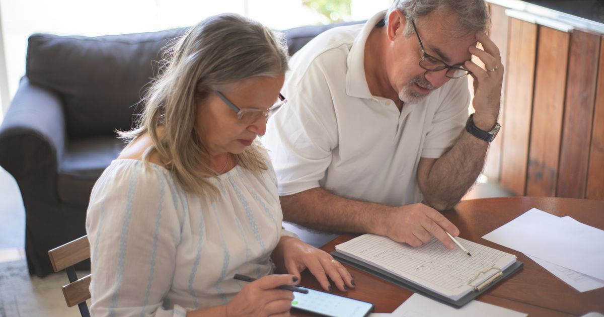 Casal de idosos revisando contas e documentos em casa